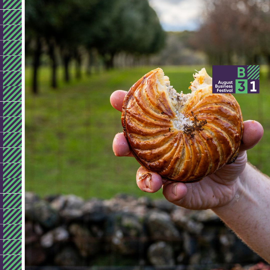 Person holding a half-eaten pastry outdoors.
