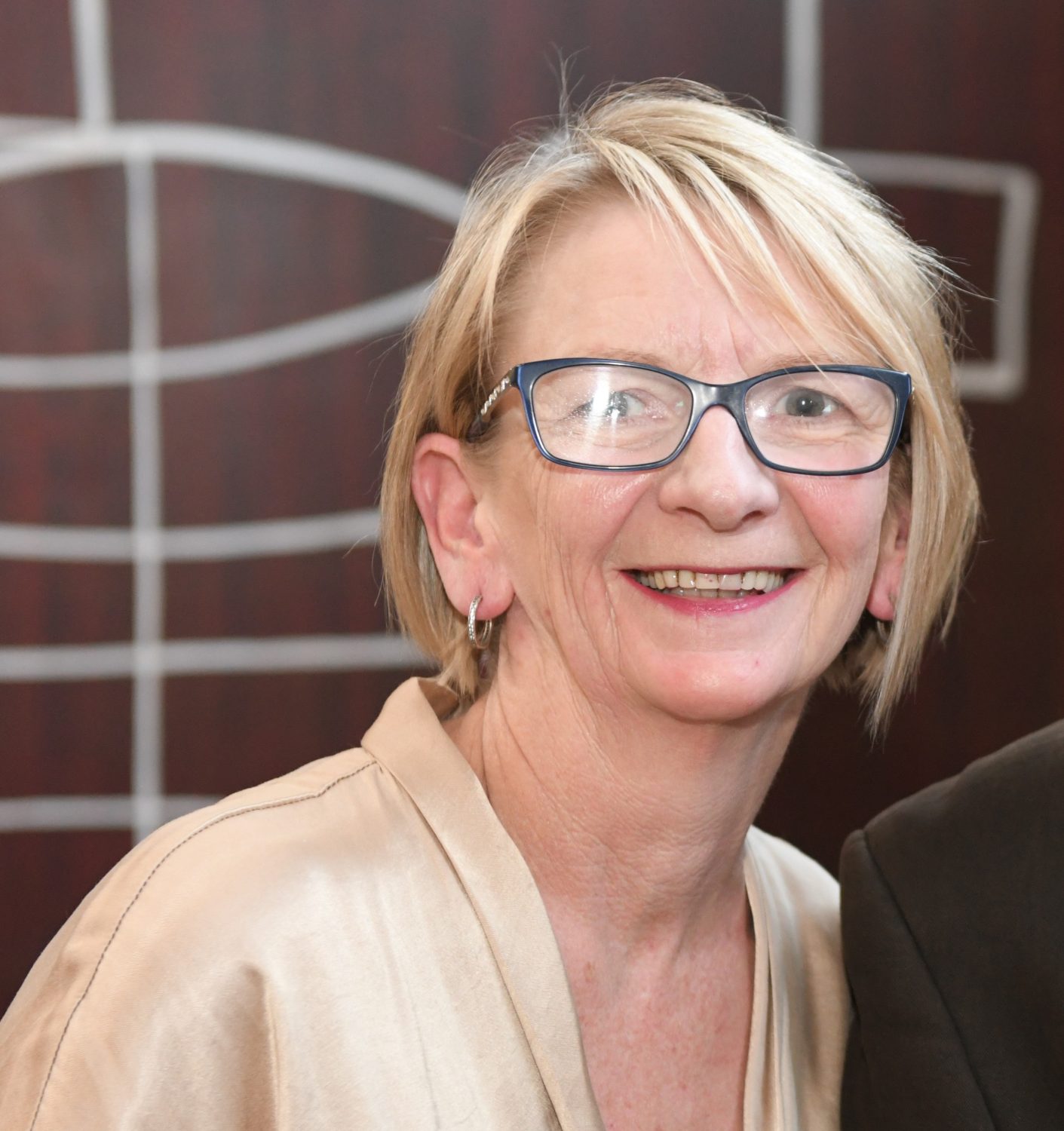 Smiling person with short hair and glasses
