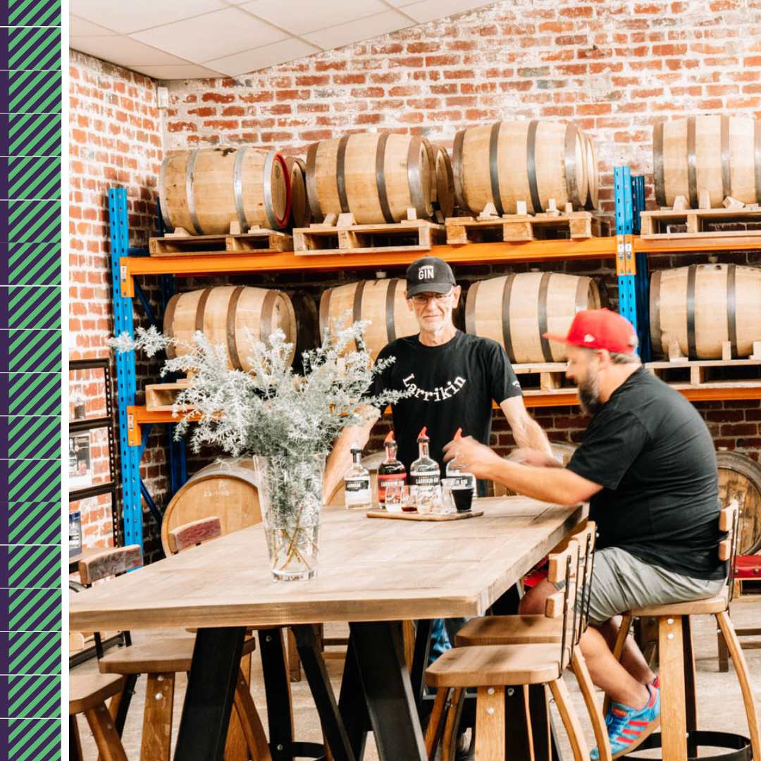 Two men tasting whiskey in a distillery.