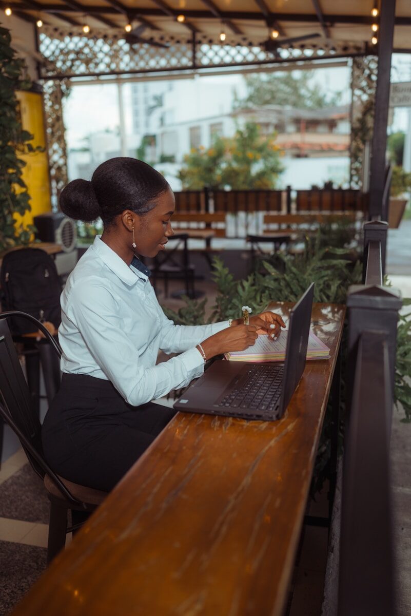A woman working on a laptop at an outdoor cafe.